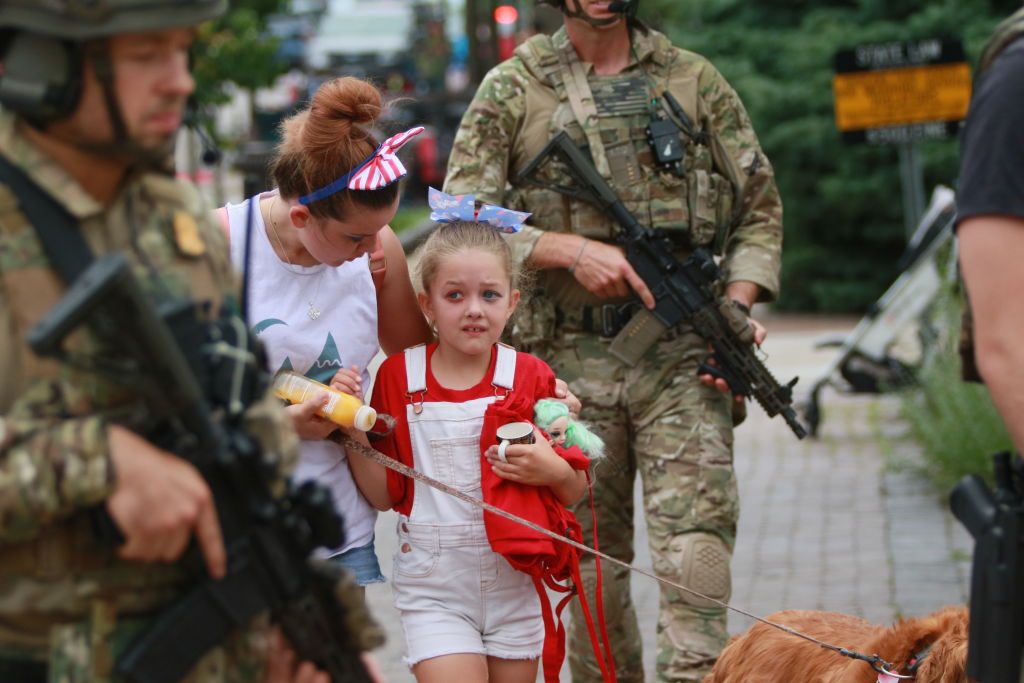 HIGHLAND PARK, ILLINOIS - JULY 04: Law enforcement escorts a family away from the scene of a shooting at a Fourth of July parade on July 4, 2022 in Highland Park, Illinois. Police have detained Robert “Bobby” E. Crimo III, 22, in connection with the shooting in which six people were killed and 19 injured, according to published reports. (Photo by Mark Borenstein/Getty Images)