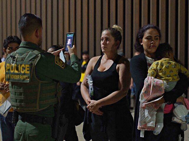 A US Border Patrol officer holds his smartphone and scans the face of a woman who illegally crossed the US-Mexico border in Yuma, Arizona in the early morning of July 11, 2022. - Every year, tens of thousands of migrants fleeing violence or poverty in Central and South America attempt …