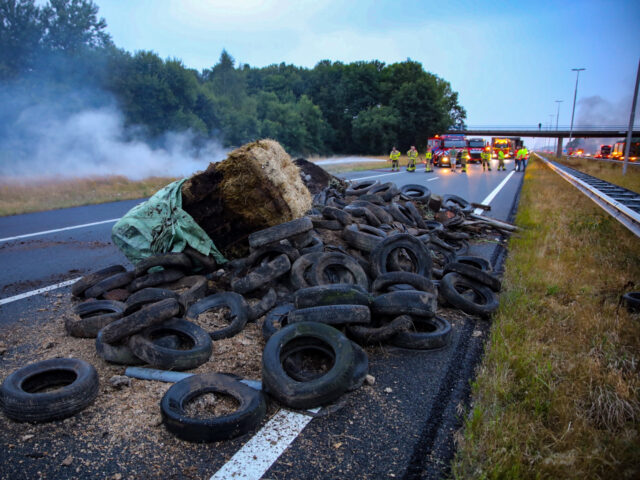 This photograph taken on July 27, 2022, shows a pile of manure, tires and hay bales on fire on the A50 highway with firefighters in the background during a farmers' demonstration against the government's nitrogen policy, in Apeldoorn, the Netherlands, on July 27, 2022. - Netherlands OUT (Photo by ANP …
