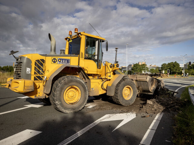 A driver in a digger vehicule pushes debris dumped during a farmers' demonstration against