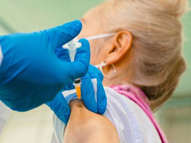 A close-up photo of a senior woman while getting vaccinated.