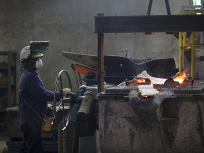 A worker manipulates a cask of molten iron before pouring it into molds to make cast iron