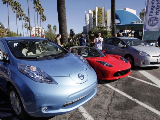 From left, electric cars from Nissan, Tesla, and Toyota are presented at a news conference