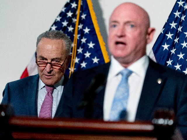 Sen. Mark Kelly, D-Ariz., right, accompanied by Senate Majority Leader Chuck Schumer of N.Y., left, speaks at a news conference following a Democratic policy luncheon on Capitol Hill in Washington, Tuesday, Feb. 8, 2022. (AP Photo/Andrew Harnik)