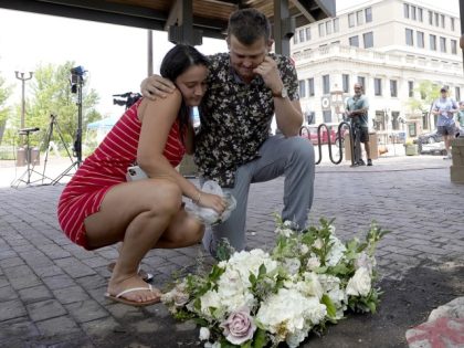 Brooke and Matt Strauss, who were married Sunday, pause after leaving their wedding bouquets in downtown Highland Park, Ill., a Chicago suburb, near the scene of Monday's mass shooting, Tuesday, July 5, 2022. (Charles Rex Arbogast/AP)