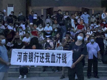 People hold banners and chant slogans stage a protest at the entrance to a branch of China's central bank in Zhengzhou in central China's Henan Province on July 10, 2022. A large crowd of angry Chinese bank depositors faced off with police Sunday, some reportedly injured as they were roughly …