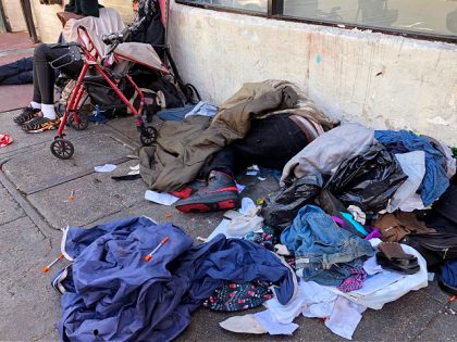 FILE - People sleep near discarded clothing and used needles on a street in the Tenderloin