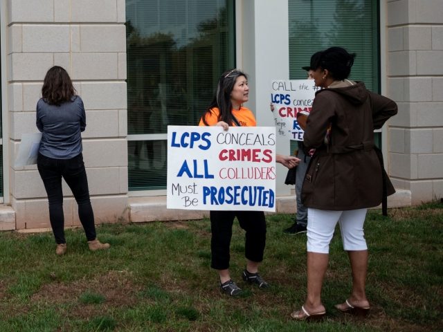 Protesters and activists hold signs as they stand outside a Loudoun County Public Schools