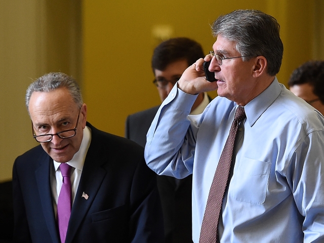 WASHINGTON, DC - NOVEMBER 13: Sen.  Charles Schumer (L) (D-NY) passes Sen.  Joe Manchin (D-WV) (R) as Manchin speaks on the phone outside the room where Democrats met for their weekly policy lunch at the US Capitol on November 13, 2014 in Washington, DC.  Manchin and Senator Claire McCaskill (D-MO) voted earlier in the day against the election of Senator Harry Reid (D-NV) as leader of the Senate Democratic caucus.  (Photo by Win McNamee/Getty Images)