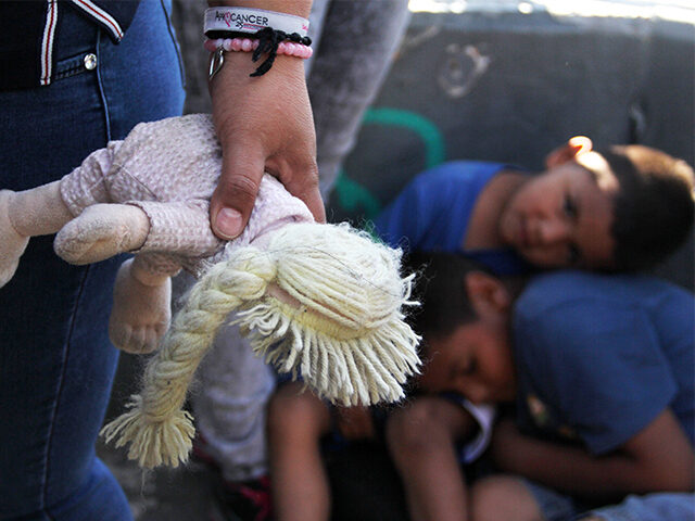 En mexikansk kvinna håller en docka bredvid barn i Paso Del Norte Port of Entry, vid gränsen mellan USA och Mexiko i delstaten Chihuahua, Mexiko den 20 juni 2018. - USA:s president Donald Trump sa på onsdagen att han skulle underteckna en verkställande order om att behålla migrantfamiljer tillsammans vid gränsen...