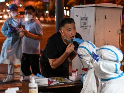 A health worker takes a swab sample from a man to test for the Covid-19 coronavirus in the Huangpu district of Shanghai on July 12, 2022. (Photo by Hector RETAMAL / AFP) (Photo by HECTOR RETAMAL/AFP via Getty Images)