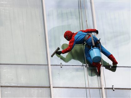 SURABAYA, INDONESIA - JULY 12: Indonesian 'Spider-Man' window cleaner, 37-year-old Teguh cleans the glass windows of the 18-storey Alana Hotel on July 12, 2013 in Surabaya, Indonesia. Teguh is a specialist glass window cleaner working on high-rise buildings wearing a Spider-Man uniform and working at an altitude of over 500 …