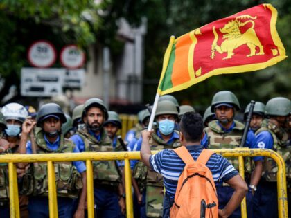 A demonstrator waves a Sri Lankan flag near police barriacdes during a protest march towar