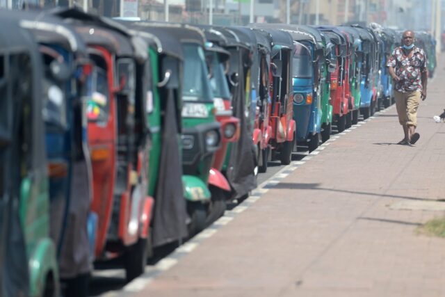 A man walks past autorickshaws waiting in a long queue at a petrol station in Colombo on J