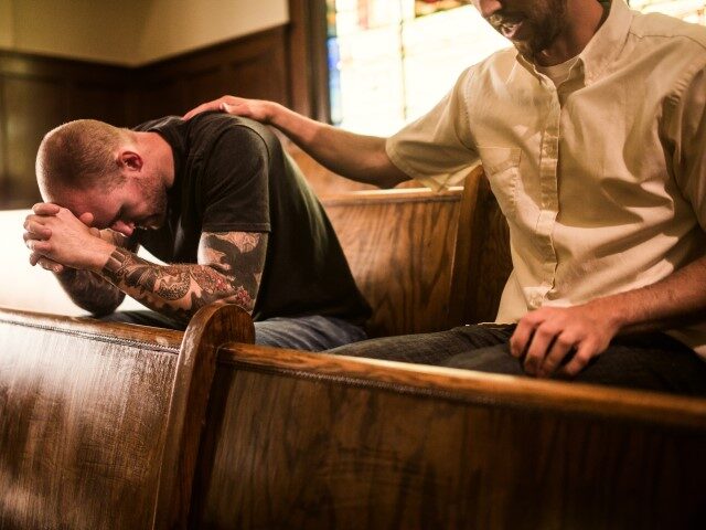A man prays for another man in church