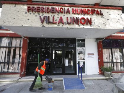 A worker sweeps up outside City Hall riddled with bullet holes, in Villa Union, Mexico, Monday, Dec. 2, 2019. The small town near the U.S.-Mexico border began cleaning up Monday even as fear persisted after 23 people were killed in a weekend gun battle between a heavily armed drug cartel …