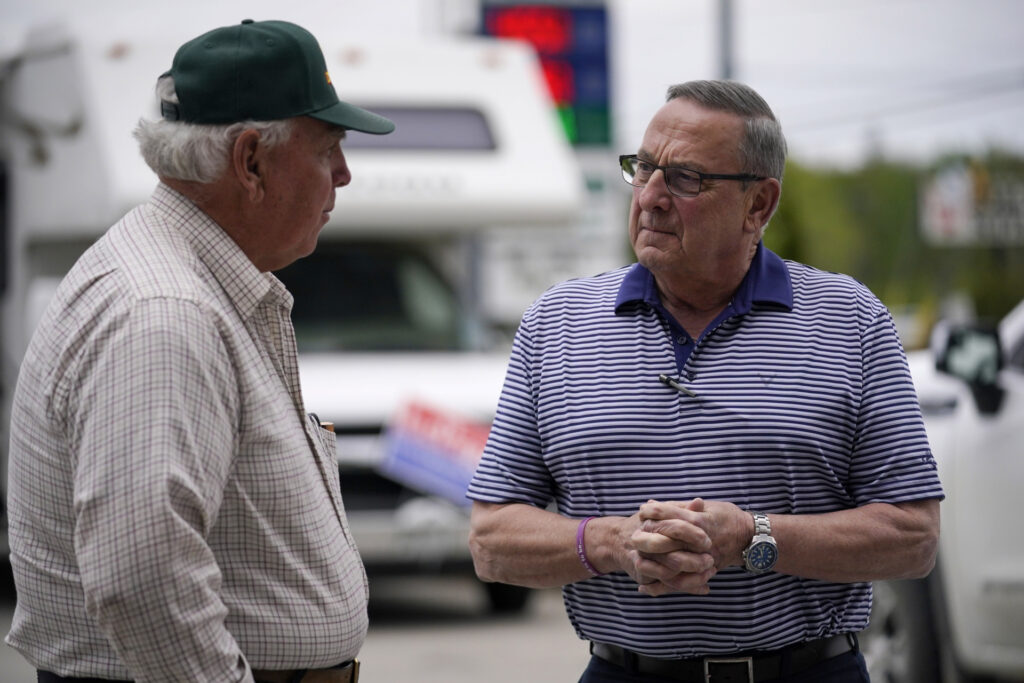 CORRECTS CITY TO BANGOR NOT HERMON Paul LePage, Republican candidate for governor, right, speaks to a man during a campaign stop outside Dysart's Restaurant and Pub, Thursday, May 19, 2022, in Bangor, Maine. (AP Photo/Robert F. Bukaty)
