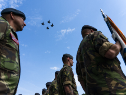 Dutch servicemen stand at attention as F-35 fighter jets fly over during a ceremony at Vol