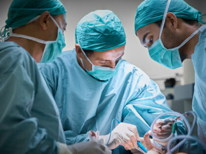 Plastic surgeons operating patient for breast implant. Team of doctors are in scrubs at op