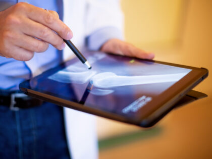 Close-up of a orthopedic physician looking at the medical scan of a patient on his digital tablet. Cropped shot of doctor reviewing patients leg x-ray on his tablet pc.