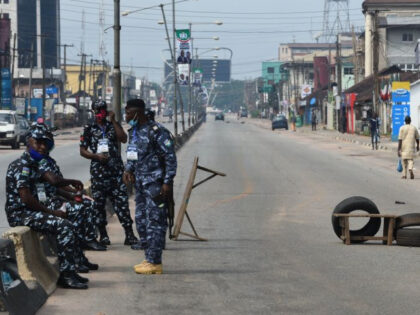 Police officers sit on fences next to a blocked road during the Edo State governorship elections in Benin City, Midwestern Nigeria, on September 19, 2020. - Hundreds of thousand voters gathered at the polls in Edo State, Midwestern Nigeria to elect a new governor or re-elect the incumbent governor, Godwin …