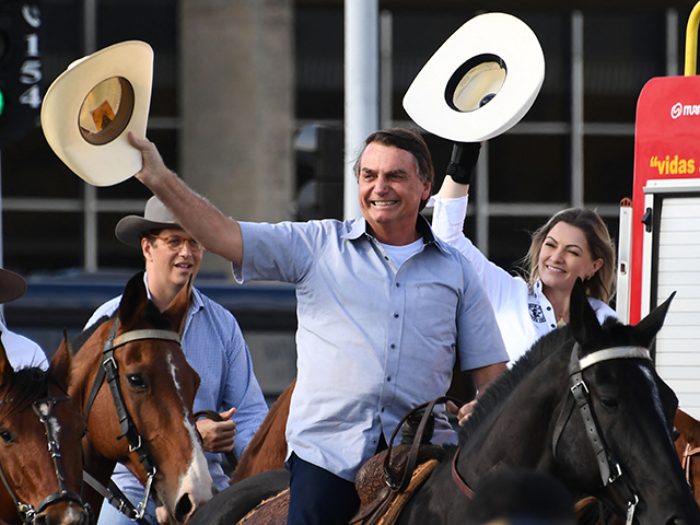 Brazilian President Jair Bolsonaro (C) arrives on horseback at a demonstration by farmers