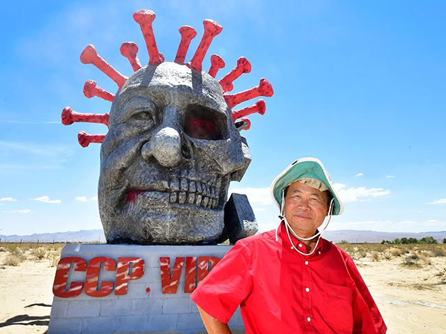 Artist and sculptor Chen Weiming poses beside his latest sculpture "ccp virus" on display