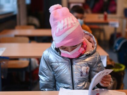 A girl wears a hat, a face mask and a winter jacket as she attends lessons in her aerated classroom at the Petri primary school in Dortmund, western Germany, on November 23, 2021 amid the novel coronavirus / COVID-19 pandemic. (Photo by Ina FASSBENDER / AFP) (Photo by INA FASSBENDER/AFP …