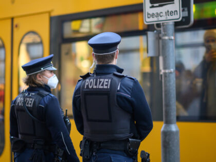 23 November 2021, Saxony, Dresden: Police officers stand at a DVB tram stop in Dresden city centre. The Dresden police department is monitoring compliance with the new Corona rules on a daily basis with 50 officers. Accordingly, the focus is on controls of the FFP2 mask obligation in public transport …