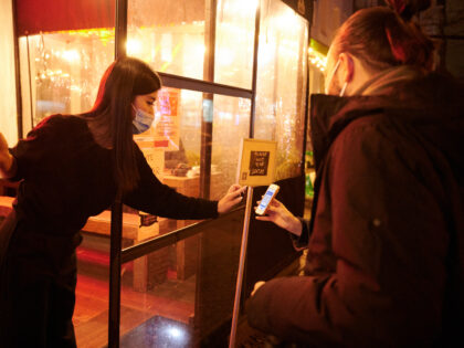 15 January 2022, Berlin: A restaurant employee checks the vaccination status of two people