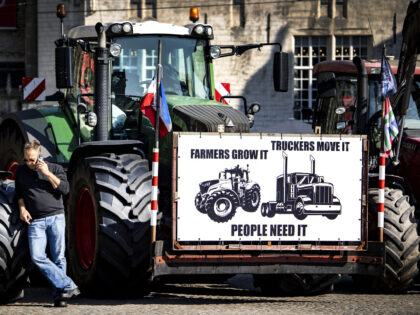 A man speaks on a smartphone next to a tractor with a placard during a rally of the Nether