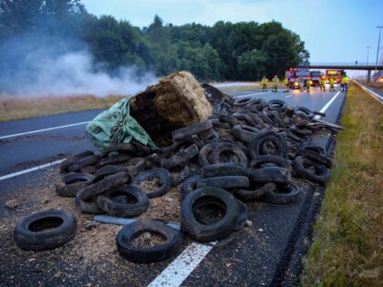 This photograph taken on July 27, 2022, shows a pile of manure, tires and hay bales on fire on the A50 highway with firefighters in the background during a farmers' demonstration against the government's nitrogen policy, in Apeldoorn, the Netherlands, on July 27, 2022. - Netherlands OUT (Photo by ANP …