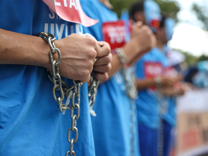 Demonstrators with chains on their hands and feet hold a protest as part of the worldwide