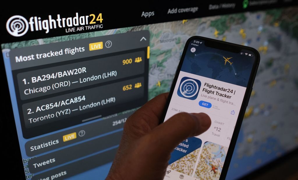 In this illustrative photo, the Flightradar24 app is seen on a smartphone in front of a screen showing the live location of planes tracked by the app in the Los Angeles, California area on August 5, 2022. - How to disrupt Russian cargo companies transportation, Elon Musk, the Chinese authorities and Kylie Jenner in one move?  Watch their jets.  Flight-tracking websites and Twitter accounts offer real-time views of air traffic — and sometimes breaking news like Nancy Pelosi's trip to Taiwan — but this exposure is prompting reactions ranging from complaints to gear seizures.  (Photo by Chris Delmas/AFP) (Photo by CHRIS DELMAS/AFP via Getty Images)