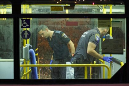 Israeli security inspect a bus after an attack outside Jerusalem's Old City, August 14, 2022. - Israeli police said they had arrested a suspect in a pre-dawn gun attack on a bus in central Jerusalem that wounded eight people according to an updated casualty toll. (Photo by AHMAD GHARABLI / …