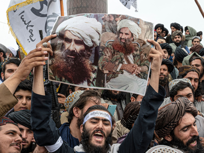 A Taliban fighter holds a poster of late Afghan leader of the Haqqani network Jalaluddin Haqqani while chanting victory slogans at the Ahmad Shah Massoud Square near the US embassy in Kabul on August 15, 2022. - Taliban fighters chanted victory slogans next to the US embassy in Kabul on …