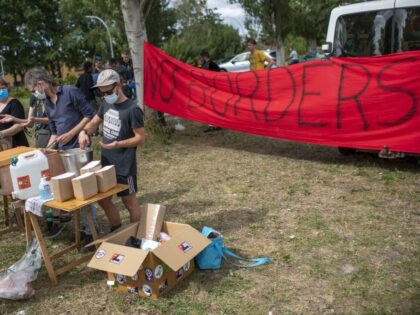 Volunteers offer food as hundreds of asylum seekers, sleeping outdoors, wait at the regist