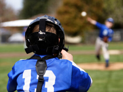 A young catcher receiving a pitch.
