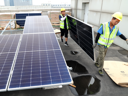 Workers install solar panels on the roof of factory buildings at a small and medium-sized