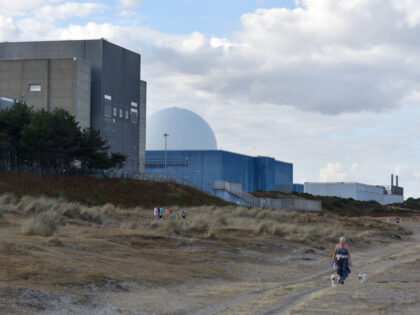SIZEWELL, ENGLAND - AUGUST 20: A woman walks her dogs along the beach next to the Sizewell B nuclear power station on August 20, 2022 in Sizewell, England. In the final weeks of his premiership the prime minister Boris Johnson has approved funding for a new nuclear power station known …