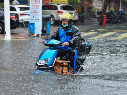 A cyclist rides along a flooded street during a heavy rainfall brought by typhoon Ma-on on August 25, 2022 in Haikou, Hainan Province of China. Typhoon Ma-on, the ninth this year, made landfall in Guangdong province on Thursday morning. (Photo by Luo Yunfei/China News Service via Getty Images)