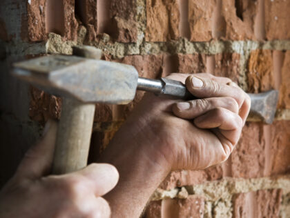 a craftsman working with hammer and chisel on a brick wall