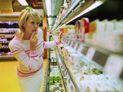 Young woman looking at dairy produce in supermarket