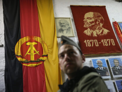 SUHL, GERMANY - OCTOBER 17: A visitor dressed as an East German NVA army soldier looks at memorabilia of the former communist East Germany (DDR), including the East German flag and portraits of Karl Marx, Vladimir Lenin and Erich Honecker, during an overnight stay in the Bunkermuseum Frauenwald on October …