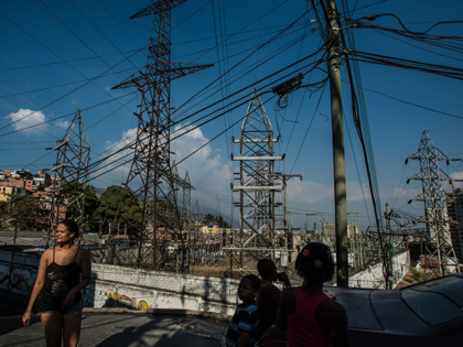 People walk past an electrical substation run by Corpoelec, a state power corporation, in the Catia slum, regularly subject to state-mandated electricity rationing, in Caracas, Venezuela, on Tuesday, March 22, 2016. Venezuela shut down for a week as the government struggles with a deepening electricity crisis. The government has rationed …