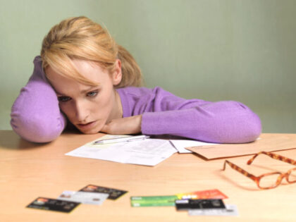 Girl with credit cards and debt with head on desk.