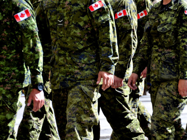 A group of Canadian soldiers wearing green camouflage uniforms march together.