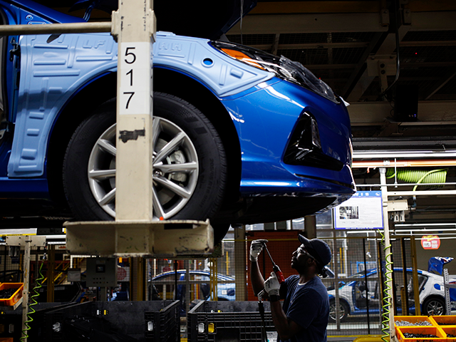 An employee uses a drill underneath a vehicle on the production line at the Hyundai Motor