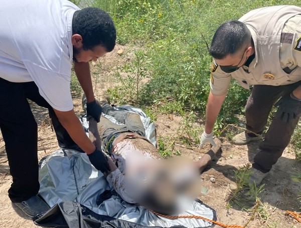 A Maverick Count Sheriff's Office deputy assists in the recovery of a drowned migrant near Eagle Pass, Texas. (U.S. Border Patrol/Del Rio Sector)