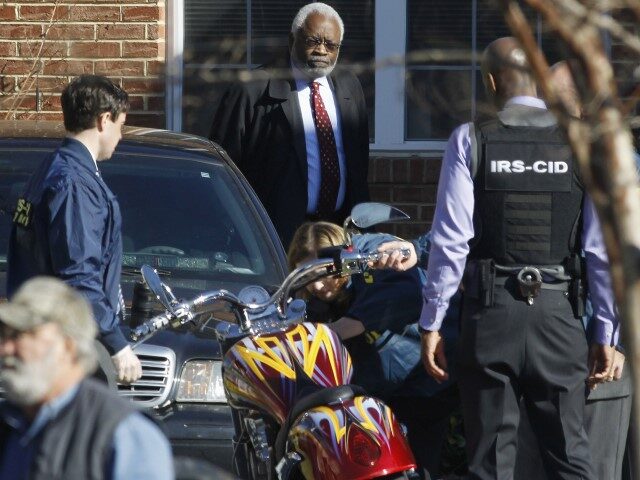 Attorney Fred Cooke, rear center, watches as agents seize a motorcycle outside the house of Washington D.C. Councilmember Harry Thomas Jr., in Washington, Friday, Dec. 2, 2011. FBI and IRS agents searched Thomas' home as part of an investigation that he diverted $300,000 in city funds for personal use. (Charles …